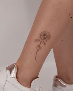 a woman's foot with a small sunflower tattoo on her left side leg