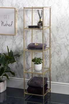 a gold shelf with towels and plants on it in front of a marbled wall