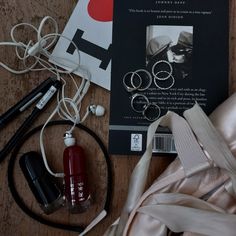 the contents of a woman's purse and accessories laid out on a wooden surface