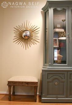 a gray china cabinet sitting next to a wooden bench on top of a hard wood floor