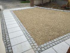 a graveled area in front of a house with brick edging and pavers