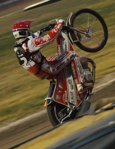 a man riding on the back of a motorcycle while holding onto his bike's handlebars