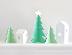 paper christmas trees and houses on a mantle in front of a white wall with the word hoorayapaper