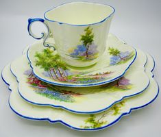 three cups and saucers are stacked on top of each other with trees painted on them