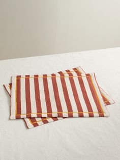 two red and white striped placemats sitting on top of a bed next to each other