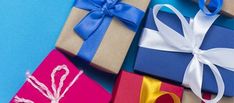 several wrapped gift boxes with ribbons and bows on blue background, closeup view from above