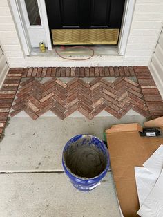 a blue bucket sitting on top of a cement floor next to a brick wall and door