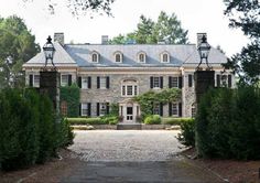 a large stone house surrounded by greenery and trees in front of it's entrance