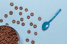 a bowl full of cereal with a spoon next to it on a blue table top