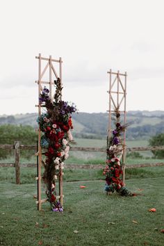 an outdoor ceremony set up with flowers and greenery on the grass in front of a wooden fence