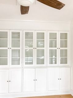 an empty room with white cabinets and a ceiling fan