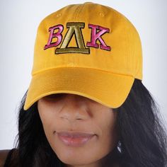 a woman wearing a yellow baseball cap with the letters bak on it's side