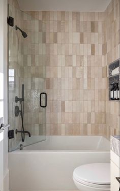 a white toilet sitting next to a bath tub in a bathroom with tiled walls and floor