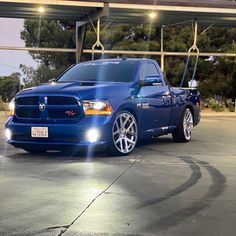 a blue truck parked in front of a parking lot with lights on it's headlamps