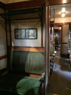 the inside of a train car with green seats and pictures on the wall above it