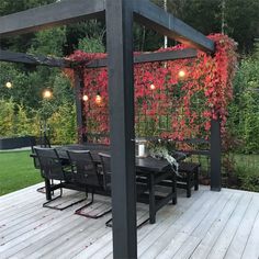 an outdoor dining area with table and chairs on the deck, surrounded by greenery