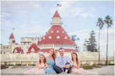 a family sitting on the beach in front of a building