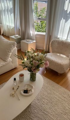 a living room filled with furniture and flowers on top of a coffee table in front of a window