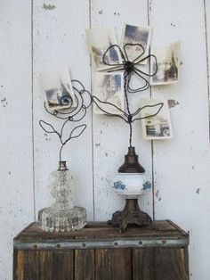 a vase with flowers on top of a wooden table next to pictures and a lamp