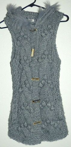 This listing is for a women's size medium/large COZY S&S Casual gray knit front button sleeveless cardigan sweater. This sweater features a hood trimmed in faux fur and front side pockets. The fabric is Acrylic/wool blend. It measures 17 inches across the armpits, 30 inches top of shoulder down to bottom in length. Excellent like new condition! No stains, fading, snags, pilling, or odors. All of my listings come from a smoke free/pet free home. I will ship out within 24 hours of receiving cleare Knitted Winter Vest, Winter Sweater Vest For Cold Weather, Winter Sleeveless Sweater Vest For Cold Weather, Sleeveless Sweater Vest For Winter, Knit Vest For Winter, Chunky Knit Sleeveless Vest For Winter, Chunky Knit Sleeveless Winter Vest, Winter Chunky Knit Sleeveless Vest, Sleeveless Knit Sweater Vest For Winter