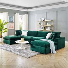 a living room with a large green couch and white pillows on the floor, in front of a gray wall