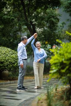 two people standing in the middle of a park, one holding his arm up to the other