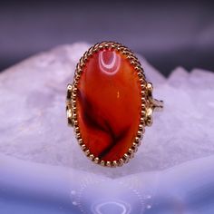 Don't miss out on this stunning vintage 14K yellow gold ring with a striking red agate cabochon at its center. The translucent agate has a rich reddish orange hue and a mystical moonstone-like shimmer. Known for its unique inclusions that resemble natural symbols, agate is a captivating member of the quartz family. This beautiful stone is elegantly set in a bezel setting, measuring around 23mm x 13.5mm. Sized at 9, this exquisite ring is marked with a 14K stamp and is in excellent vintage condit Yellow Gold Carnelian Oval Cabochon Ring, Carnelian Yellow Gold Rings With Oval Cabochon, Yellow Gold Oval Cabochon Carnelian Rings, Classic Red Agate Jewelry, 14k Gold Red Cabochon Ring, 14k Gold Cabochon Red Ring, 14k Gold Red Cabochon Ruby Ring, 14k Gold Rings With Red Cabochon, Red Ruby Oval Cabochon Ring In 14k Gold