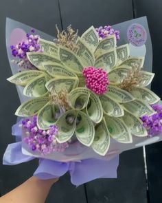 a bouquet made out of dollar bills and purple flowers