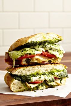 two sandwiches stacked on top of each other with pesto and tomatoes in between them