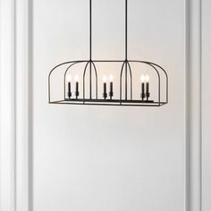 a chandelier with five candles hanging from it's center, in front of a white wall