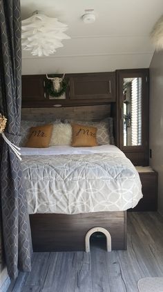 a bed with two pillows on top of it in a room that has wood floors