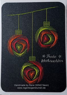 an ornament is hanging from a wire on a black card with red, green and yellow swirls