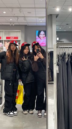 three women taking pictures in a clothing store