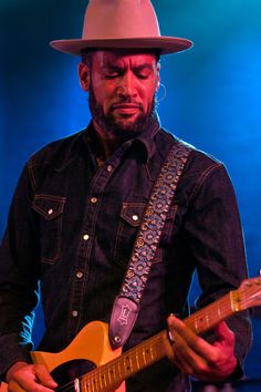 a man with a hat playing an electric guitar