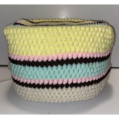 a multicolored crocheted bag sitting on top of a table next to a white wall