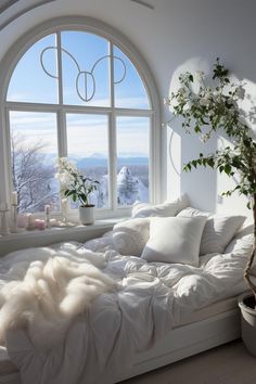 a white bed sitting in front of a window next to a potted plant on top of a table