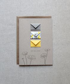 an origami envelope with yellow and gray flowers on it, next to a card