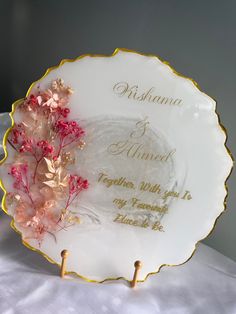 a white plate with gold trim and flowers on it, sitting on top of a bed