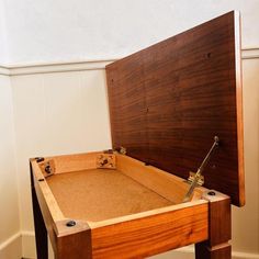 an open wooden box sitting on top of a hard wood floor next to a wall