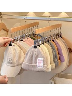 a rack with hats hanging from it's hooks and two hands reaching for them