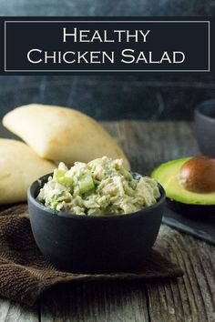 a bowl filled with guacamole next to two avocados and bread