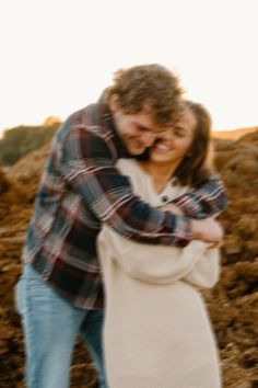 a man and woman hugging each other in the dirt