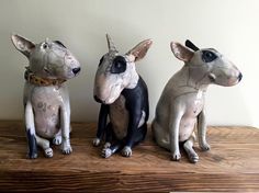 three ceramic dogs sitting on top of a wooden table