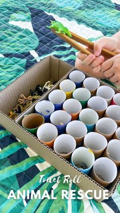 someone is holding chopsticks in front of an animal rescue box filled with cups