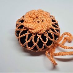 an orange and black crocheted object on a white surface