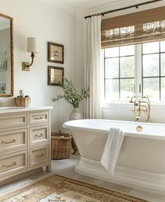 a white bath tub sitting next to a window in a bathroom under a large mirror