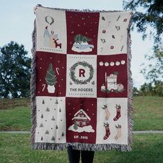 a person standing in the grass holding up a blanket that has christmas decorations on it