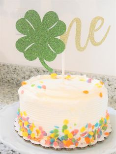 a white cake with a green leaf on top and sprinkles around it