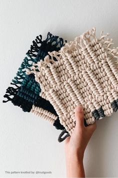 a hand is holding a knitted dishcloth in front of a white wall with blue and green accents