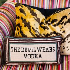 the devil wears vodka pillow sitting on top of a striped chair with a decorative pillow